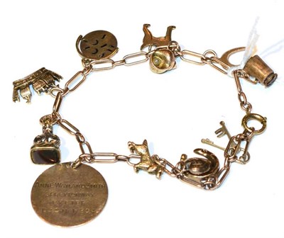 Lot 313 - A charm bracelet, suspending 12 charms, including a miniature hardstone set fob and a spaniel,...