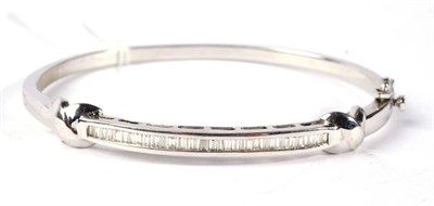 Lot 321 - A diamond bangle, the front channel set with baguette cut diamonds, between 'X' motifs, total...