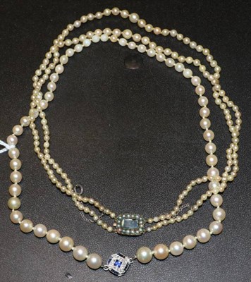 Lot 389 - A graduated double strand pearl necklace, knotted to a seed pearl set clasp with glass panel,...