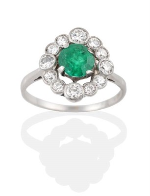 Lot 145 - An Early Twentieth Century Emerald and Diamond Cluster Ring, a round cut emerald in a claw setting