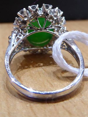 Lot 157 - A Jade and Diamond Cluster Ring, an oval cabochon jade in a claw setting, within a border of...
