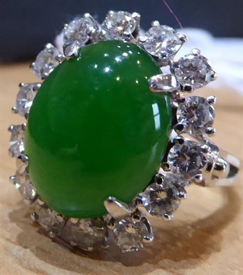 Lot 157 - A Jade and Diamond Cluster Ring, an oval cabochon jade in a claw setting, within a border of...