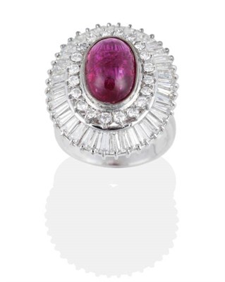 Lot 177 - A Ruby and Diamond Cluster Ring, an oval cabochon ruby in a rubbed over setting, within a two...