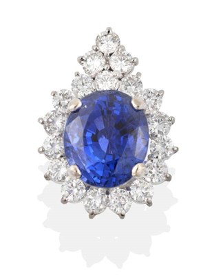 Lot 183 - A Sapphire and Diamond Cluster Pendant, an oval cut sapphire in a claw setting, within a border...