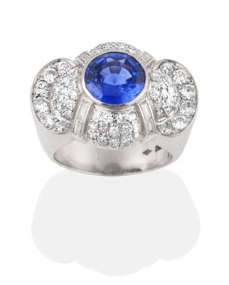Lot 229 - A Circa 1950s Sapphire and Diamond Cluster Ring, a round cut sapphire in a rubbed over setting,...