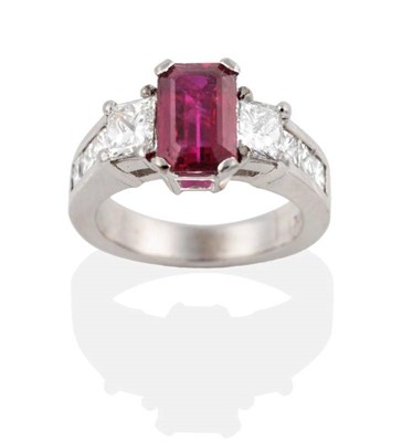 Lot 241 - A Ruby and Diamond Ring, an octagonal cut ruby in a claw setting, spaced by princess cut...