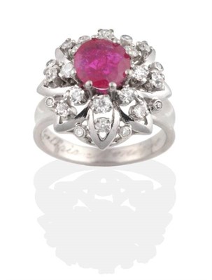 Lot 249 - A Ruby and Diamond Cluster Ring, a round cut ruby in a claw setting within a diamond set petal...