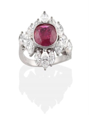 Lot 255 - A Ruby and Diamond Cluster Ring, an oval cut ruby in a rubbed over setting within a border of...