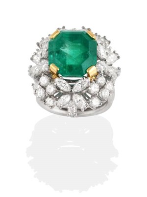 Lot 256 - An Emerald and Diamond Cluster Ring, a square octagonal cut emerald in a claw setting within border