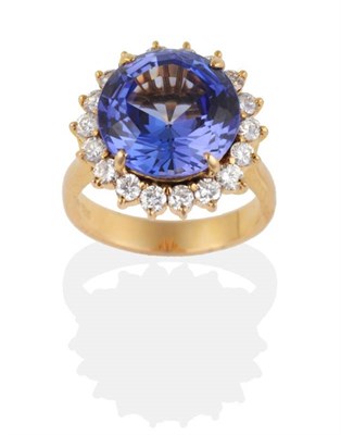 Lot 295 - A Tanzanite and Diamond Cluster Ring, a round mixed cut tanzanite in a claw setting, within a...