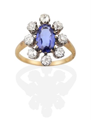 Lot 309 - A Tanzanite and Diamond Cluster Ring, an oval cut tanzanite in a claw setting, within a border...