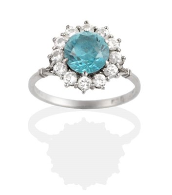 Lot 320 - A Blue Zircon and Diamond Cluster Ring, a round cut blue zircon in a claw setting within a...