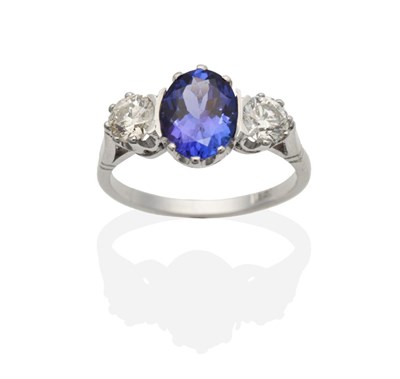 Lot 350 - A Tanzanite and Diamond Three Stone Ring, an oval cut tanzanite between two round brilliant cut...