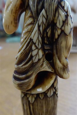 Lot 393 - A Japanese Ivory Netsuke, Edo period, modelled as a Sennin wearing a fur coat holding a clam, 9.5cm