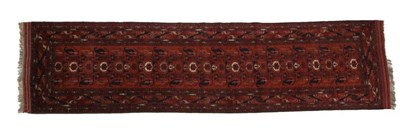 Lot 472 - Narrow Turkmen Runner North West Afghanistan, circa 1980 The rust field with a oneway design of...
