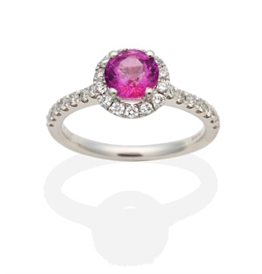 Lot 453 - A Platinum Pink Sapphire and Diamond Cluster Ring, a round cut pink sapphire in a claw setting...