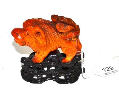 Lot 129 - A Chinese amber carved figure of a mythical beast, glued to a carved wooded base, gross weight...