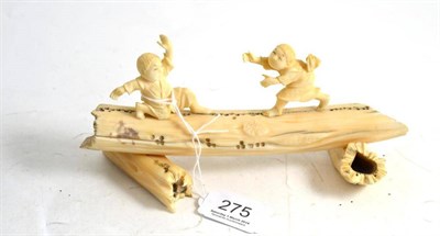 Lot 275 - A Japanese carved walrus/hippo tusk group of two boys fighting on a rustic log, circa 1920