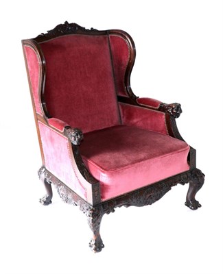 Lot 909 - A Victorian Carved Mahogany Wing-Back Chair, late 19th/early 20th century, recovered in pink...