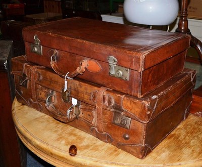 Lot 678 - Brown leather suitcase with straps and keys; and another smaller (2)