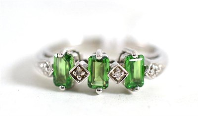 Lot 177 - A 9ct white gold green stone and diamond ring, the step cut green stones alternate with...