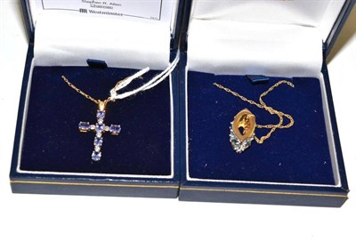 Lot 214 - A diamond and blue topaz pendant and a diamond and tanzanite cross on chain