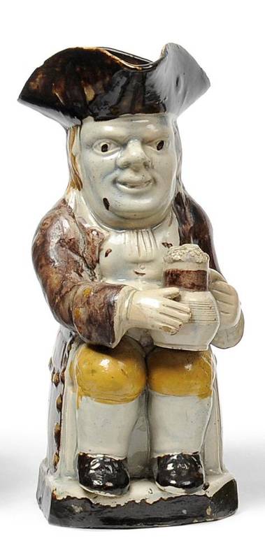 Lot 21 - A Staffordshire Pottery Toby Jug, late 18th century, the seated figure with brown hat and cloak and