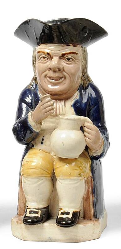 Lot 23 - A Staffordshire Pottery Toby Jug, late 18th century, the seated figure with brown hat, blue...