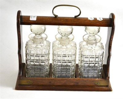 Lot 16 - Three bottle tantalus in an oak frame