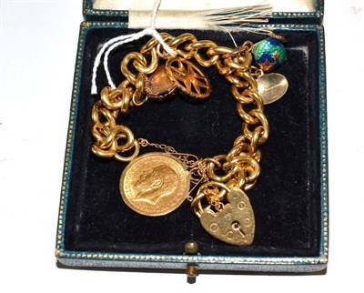 Lot 60 - A curb and lock bracelet, stamped '18', hung with five charms, including a 1911 half sovereign