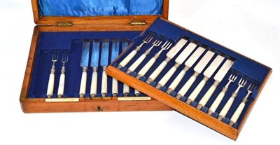 Lot 128 - A cased set of eleven silver plated and mother-of-pearl cake knives and forks, the fitted oak...