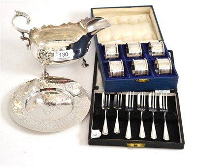 Lot 130 - A set of six silver napkin rings in original fitted case, a silver plated sauce boat, a small...