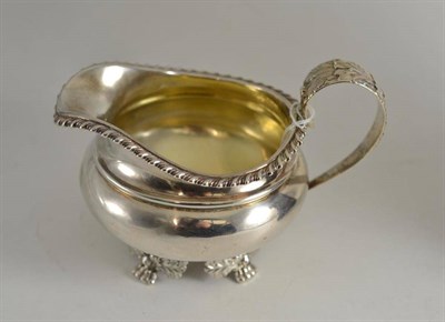 Lot 367 - A George IV silver milk jug with a gadrooned border and four paw feet, London 1825