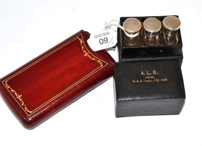 Lot 60 - Black leather case enclosing three silver mounted glass scent bottles and a leather cigar case with