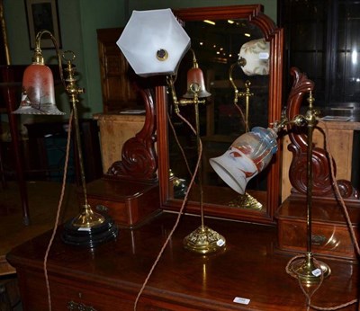 Lot 397 - Three adjustable brass table lamps with glass shades