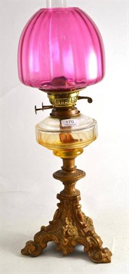 Lot 170 - Glass oil lamp with gilt metal base and cranberry shade