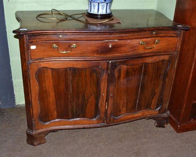 Lot 414 - A George III rosewood serpentine fronted cabinet with single drawer and brushing slide...