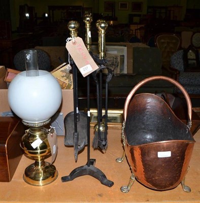 Lot 237 - A copper coal scuttle raised on paw feet, a brass companion set and a brass oil lamp