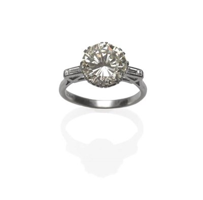 Lot 373 - A Diamond Solitaire Ring, a round brilliant cut diamond in white double claw settings, flanked by a