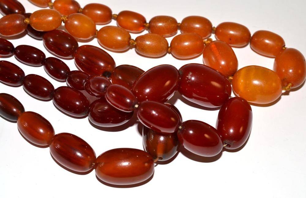 Lot 6 - Three amber necklaces, all of graduated barrel shaped beads, one a cherry red colour, one a...