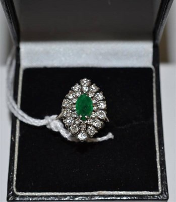 Lot 36 - An emerald and diamond cluster ring, the marquise cut emerald within a double border of round...