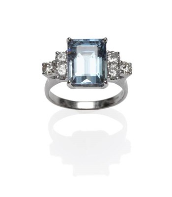 Lot 399 - An 18 Carat White Gold Aquamarine and Diamond Ring, the step cut aquamarine with a trio of...