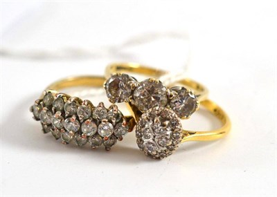 Lot 197 - An oval set diamond cluster ring, another set with three rows of small stones and a paste set...