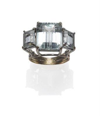 Lot 412 - An Aquamarine Three Stone Ring, the graduated step cut aquamarines in a yellow claw setting, to...