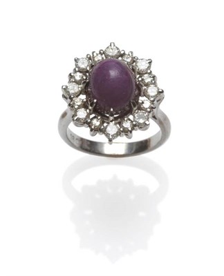 Lot 426 - A Cabochon Ruby and Diamond Cluster Ring, the oval cabochon ruby centres a border of sixteen...