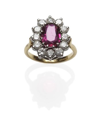 Lot 429 - An 18 Carat Gold Ruby and Diamond Cluster Ring, the oval mixed cut ruby within a border of...