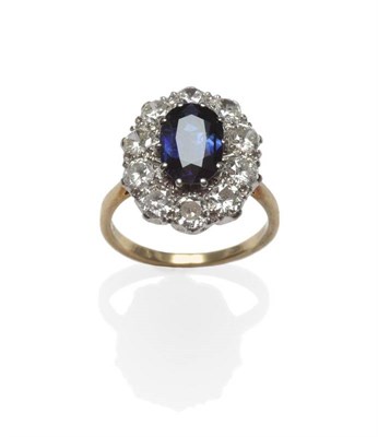 Lot 436 - A Sapphire and Diamond Cluster Ring, the oval mixed cut sapphire within a border of ten round...