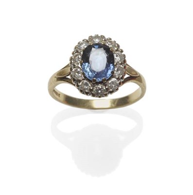 Lot 445 - An 18 Carat Gold Sapphire and Diamond Cluster Ring, the oval mixed cut sapphire within a border...