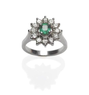 Lot 484 - An Emerald and Diamond Cluster Ring, circa 1960, the emerald-cut emerald within a border of...