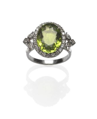 Lot 506 - An 18 Carat White Gold Peridot and Diamond Cluster Ring, the oval cut peridot within a border...